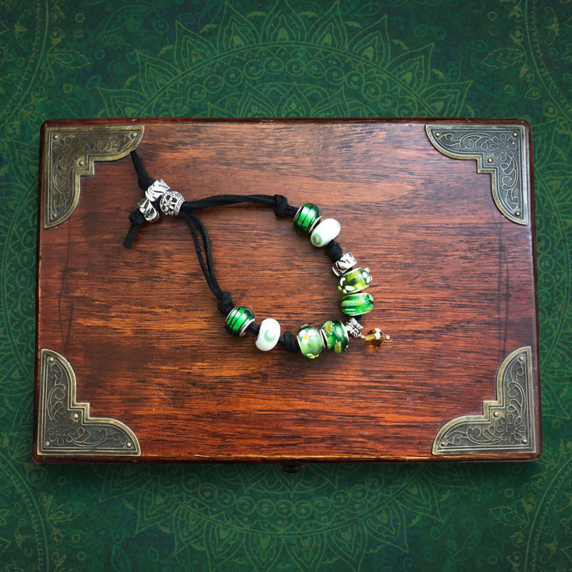Handmade green glass charm bracelet with silver metal elements and a black suede strap