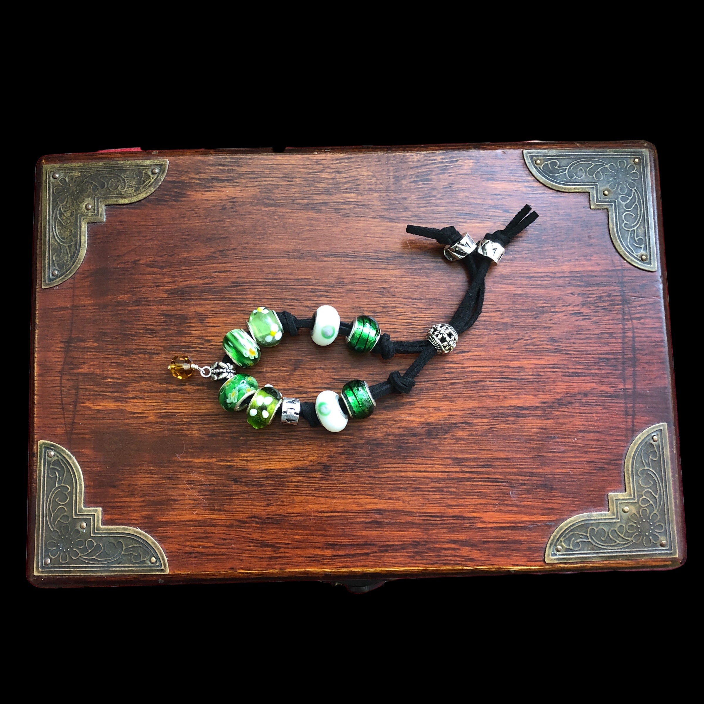 Handmade green glass charm bracelet with silver metal elements and a black suede strap